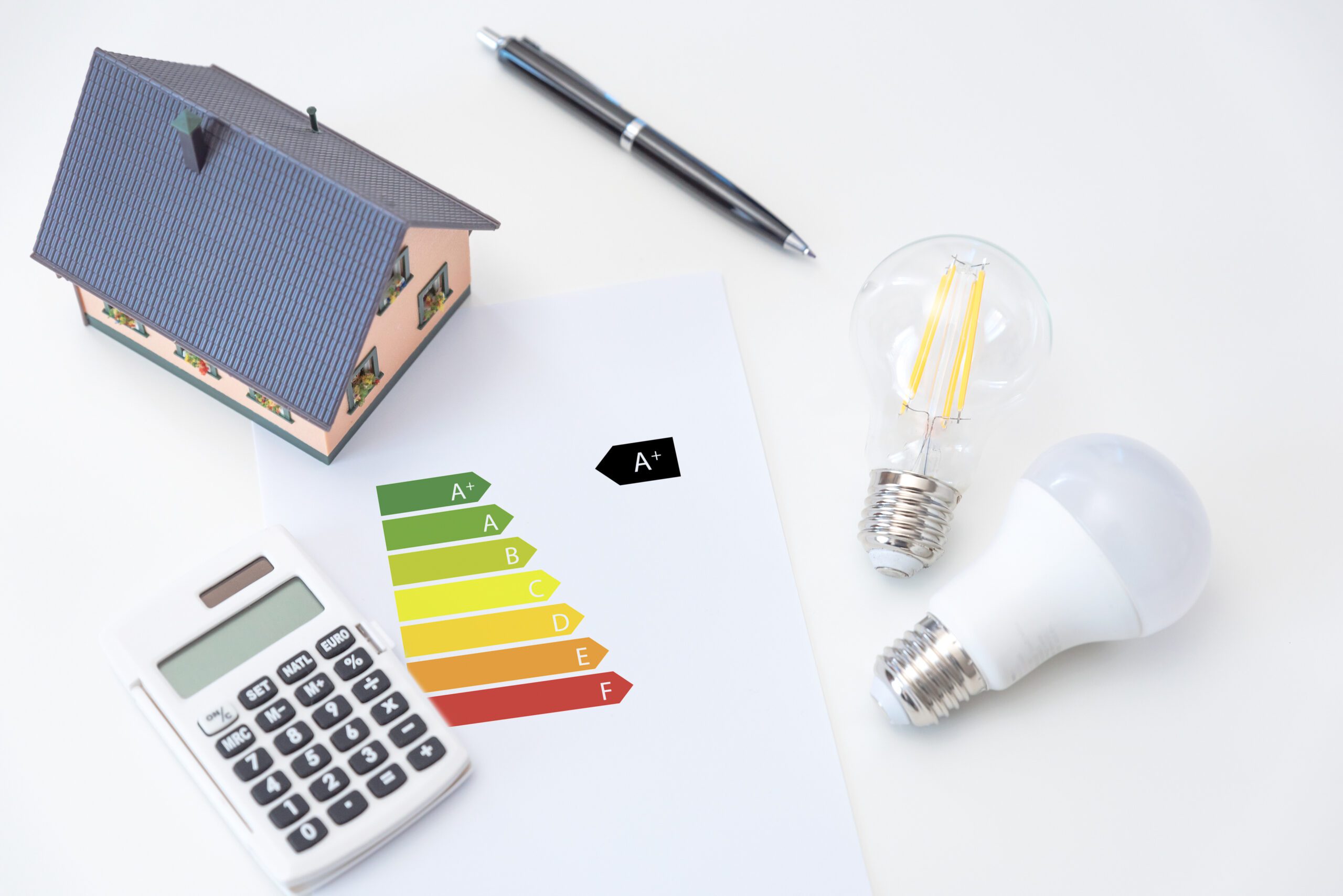 Lyspære og kalkulator som symboliserer energieffektivitet og sparing, med et energimerkingsdiagram i bakgrunnen.